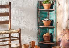 an old wooden chair sitting next to a shelf filled with potted plants and pots