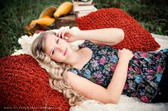 a young woman laying on top of a red blanket next to a pile of books