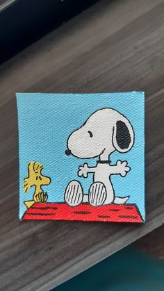 a small patch with a cartoon snoopy dog on it's lap and a yellow giraffe in the background