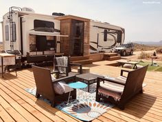 an rv parked on top of a wooden deck next to a picnic table and chairs