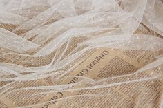 an old newspaper is covered with white lace and burlocked fabric, as if it were from the 1950's