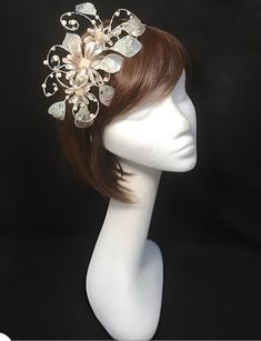 Delicate silver beige fascinator perfect for the guest who wants something fairly understated.  This design is a beautiful selection of glass effect leaves and flowers clustered together and set onto a fine comfort base tiara band. As with all our designs, this piece can be made exact to the image or in any colour combination to match in with your outfit. If a specific colour is required customers can message over an image of their outfit and accessories, or if time allows customers are always w Whimsical White Hair Accessories For Wedding, Adjustable Silver Headband Fascinator, Whimsical White Wedding Hair Accessories, Elegant Cream Headband With Handmade Flowers, Elegant Beige Wedding Headpieces, Cream Headpiece With Structured Crown For Evening, Whimsical Wedding Hair Accessories With Handmade Flowers, Elegant Cream Headband Costume, Elegant Beige Headpieces With Handmade Flowers