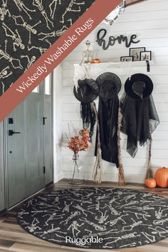 a black and white halloween themed entryway with pumpkins on the floor, witch's hats hanging from hooks