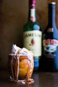 an apple covered in icing next to bottles of liquor