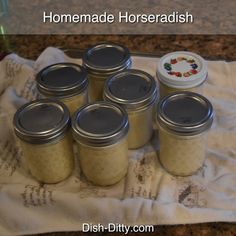 six jars of homemade horseradish sitting on a towel next to a canister