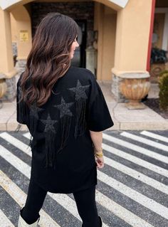 This Ain't Texas Fringed Star Sequin Patch Tee in Black Sparkle and shine in this edgy black tee featuring beaded star patches with metal fringe accents! With a relaxed fit, you'll be comfortable while standing out from the crowd. This tee ain't your average Texas shirt! Beaded Star Patches with METAL FRINGE! How COOL! 🤤 Relaxed Fit. Hand Wash Cold. Lay Flat To Dry. If You Are In-Between Sizing, Go With The Smaller of the Two Sizes. Model is Wearing the Size Small. 100% Cotton Small (2-6) Mediu Black Crew Neck T-shirt With Star Patch, Trendy Black Top With Star Patch, Black Crew Neck Top With Star Patch, Trendy Black Fringe Top, Trendy Black Top With Fringe, Black Tops With Rhinestone Fringe For Night Out, Casual Fringe Tops For Night Out, Trendy Black Tops With Rhinestone Fringe, Star Patches