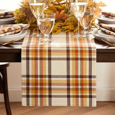 the table is set for thanksgiving dinner with plates, glasses and napkins on it