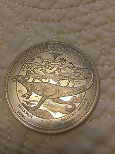 a silver coin with an image of a lizard on it