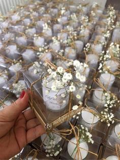 a person holding a box filled with candles and flowers on top of a table covered in clear boxes