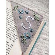 a bookmark with flowers on it and the letter s next to an open book