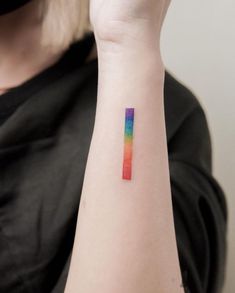 a woman's arm with a rainbow colored tattoo on the left side of her arm