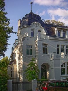 a large white building sitting next to a lush green forest