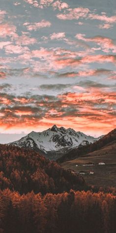 the sky is pink and orange as the sun sets in the distance over mountains with snow on them