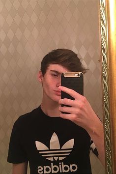 a young man taking a selfie in front of a mirror with his cell phone