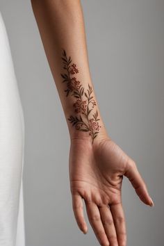 a woman's hand with a flower tattoo on her left wrist and the other arm