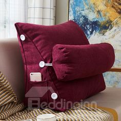 a red pillow sitting on top of a couch next to a cup of coffee and a blanket