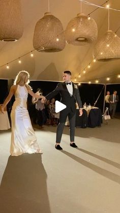 a bride and groom dance together at their wedding reception in the tented area with string lights