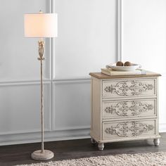 a white lamp sitting on top of a wooden floor next to a chest of drawers