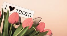 pink tulips are in a vase with i love mom sign