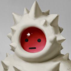 a red and white ceramic object with spikes on it's head, in front of a gray background