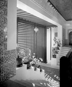 a black and white photo of a staircase in a house with decorative screens on the wall