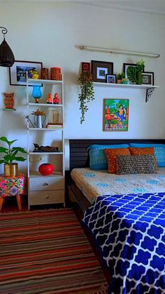 a bed room with a neatly made bed next to a shelf filled with potted plants