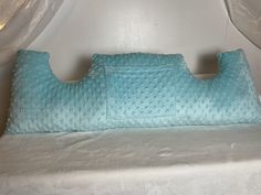 a blue pillow sitting on top of a white bed