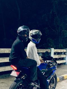 two people riding on the back of a blue motorcycle