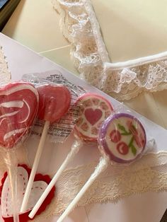 some lollipops are sitting on top of a piece of paper and lace