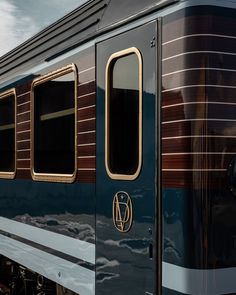 the side of a blue train car with brown stripes and gold trim on it's windows