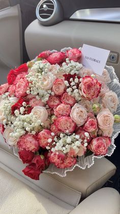 a bouquet of pink and white flowers sitting on top of a car seat