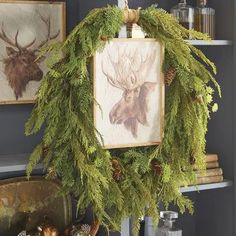 a christmas wreath is hanging on the mantle in front of two deer heads and pine cones