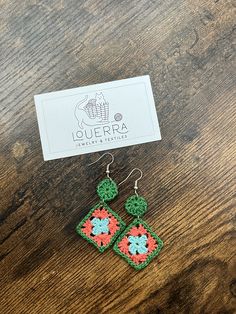 the earrings are made from crochet and have green, pink, and blue flowers on them