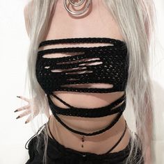 a woman with white hair wearing a black top and chains around her neck is looking at the camera