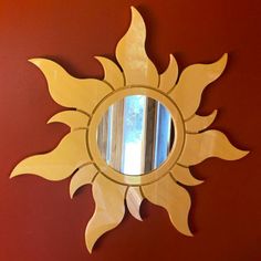 a sun shaped mirror mounted to the side of a wall next to a red wall