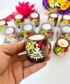 a person holding a candle in front of some flowers and candles on a table with other decorations