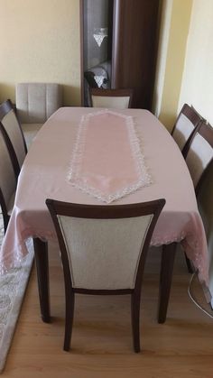 a dining room table and chairs with a pink table cloth on it's edge