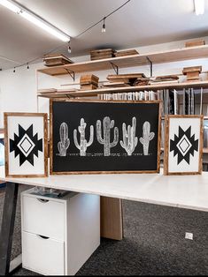 three black and white pictures hanging from the ceiling in an office area with bookshelves