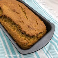 a loaf of banana bread in a pan on a table with a blue and white towel