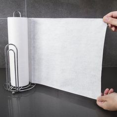 a person holding a piece of paper next to a roll of toilet paper