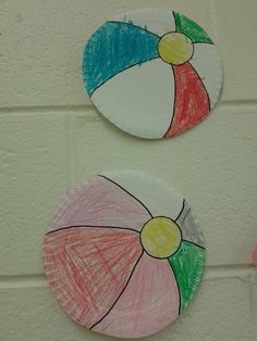 two paper plates with umbrellas painted on them hanging from the side of a wall