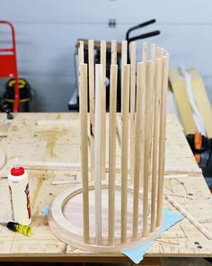 a wooden sculpture sitting on top of a table next to a glue bottle and some scissors