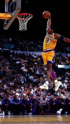 a basketball player jumping up into the air to dunk a ball in front of an audience