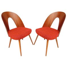 pair of mid century modern chairs with red upholstered seat cushions and wooden legs