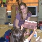 a woman holding a cake with white frosting on it while two children look at it