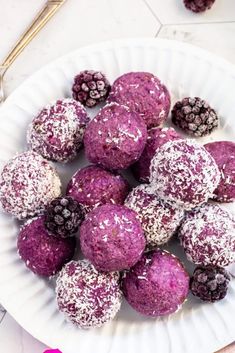 a white plate topped with purple desserts covered in powdered sugar