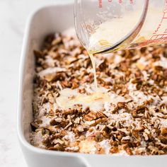 a white dish filled with oatmeal and milk being poured into it