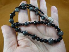 (Internal #V-445)  You are bidding on a beautiful, handmade, 18" long, silver obsidian bead necklace with 8 mm round silver obsidian beads and 6 and 7 mm black onyx round beads;  silver safety clasp closure. What you see is what you get. WE SHIP WORLDWIDE!  Other accepted payment: Credit card (Mastercard/Visa/Discover) inquire for details Handmade Obsidian Round Beads Jewelry, Polished Round Obsidian Bead Jewelry, Gray Round Spacer Beads Jewelry, Gray Single Strand Round Bead Jewelry, Gray Single Strand Jewelry With Round Beads, Silver Obsidian, Gray Gemstones, Onyx Bead, Necklace Jewelry