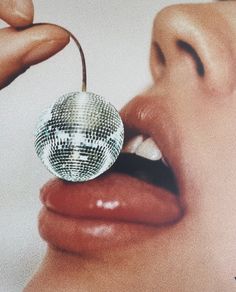 a close up of a woman's mouth with a disco ball in her lip