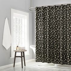 a bathroom with a black and white shower curtain next to a bathtub in front of a window